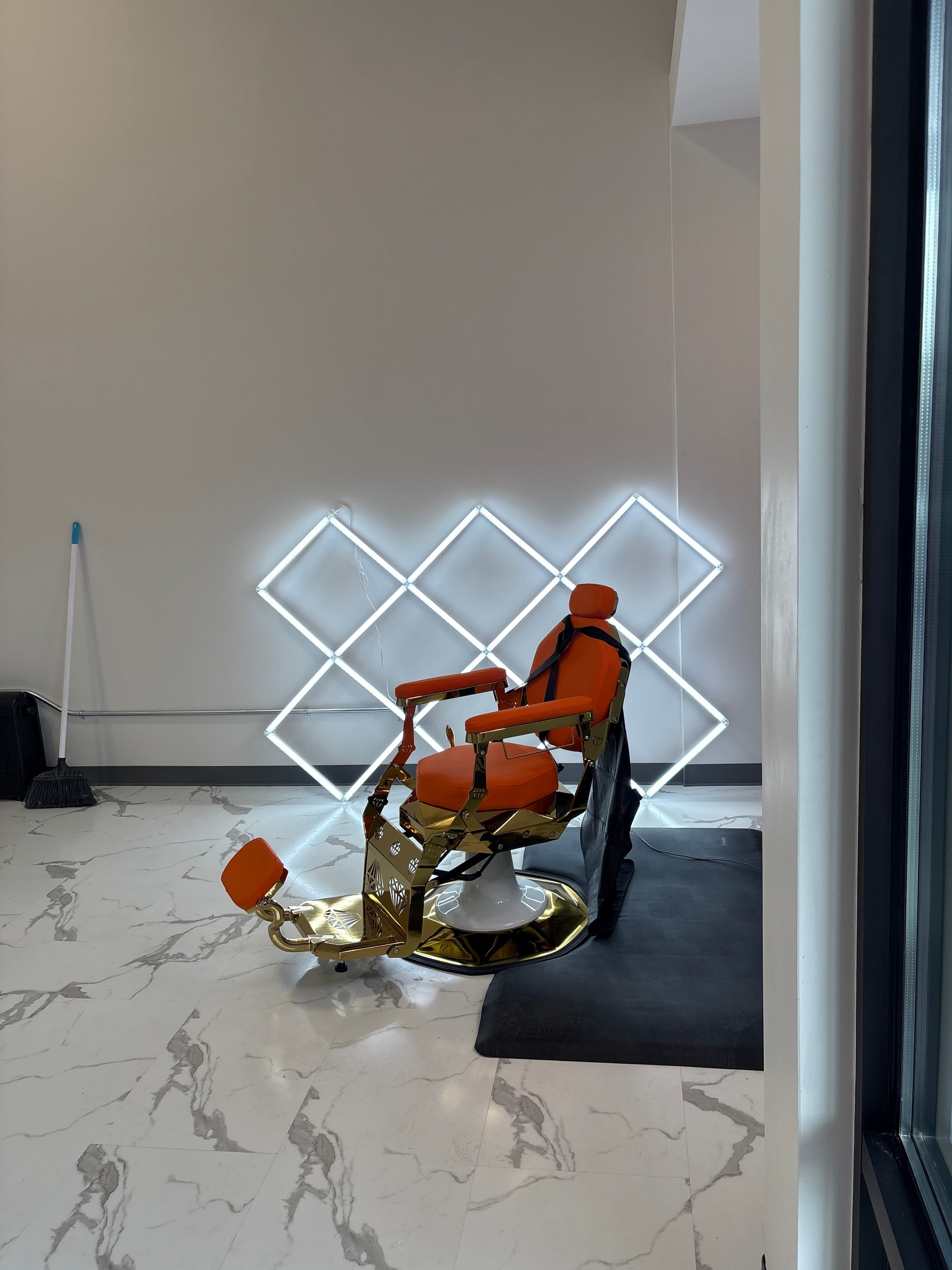 Silla de barbero dorada y naranja frente a la pared de diamante LED característica de Clean Culture Barbershop #2