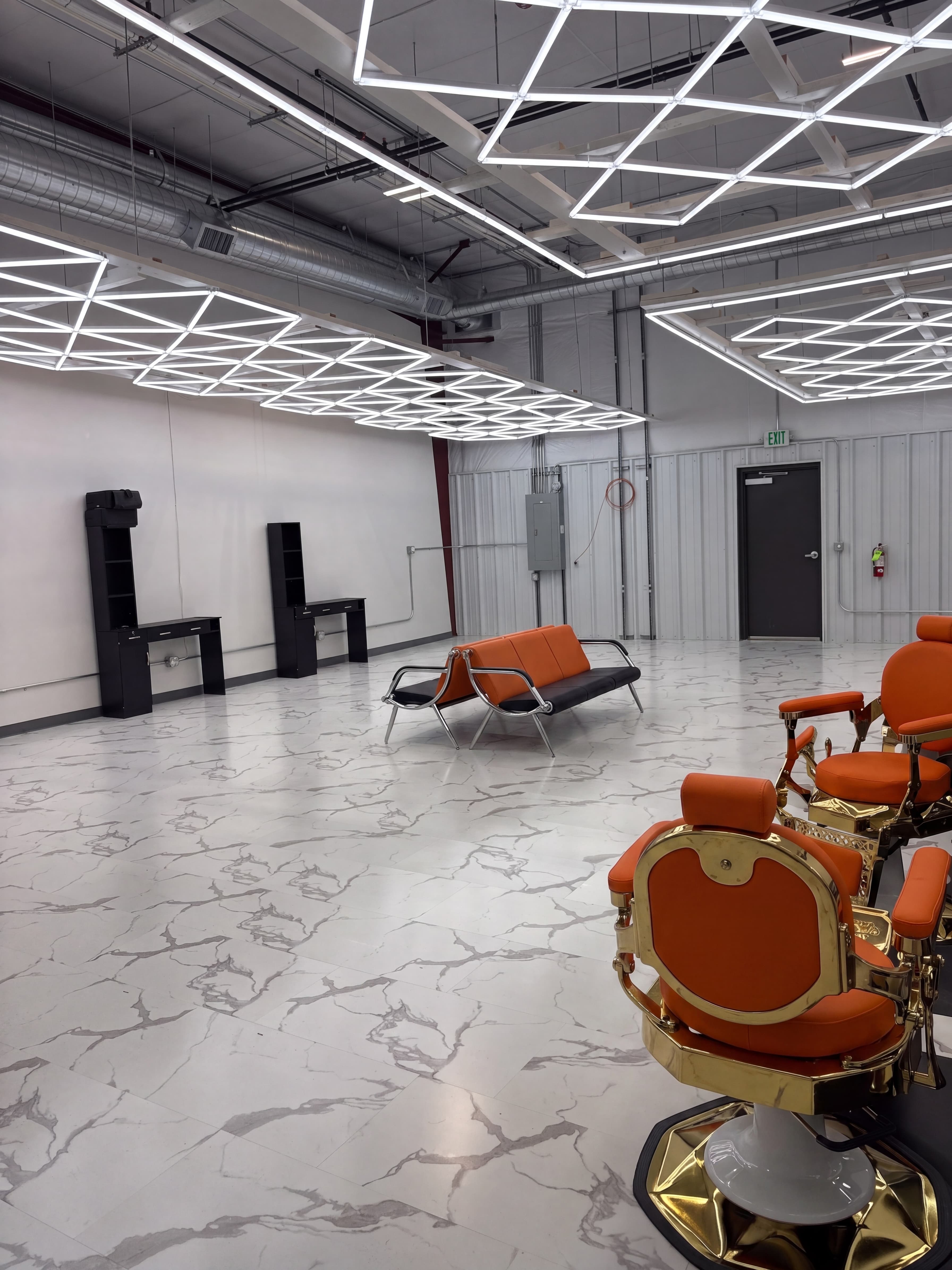 Inside Clean Culture Barbershop #2 in Pasco — geometric LED ceiling grid, gold barber chair, orange waiting bench, marble flooring